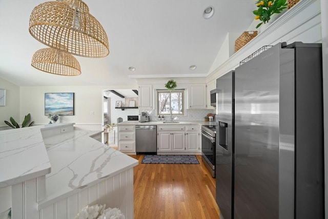 kitchen featuring appliances with stainless steel finishes, hanging light fixtures, light stone countertops, a peninsula, and white cabinetry