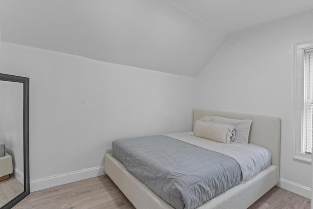 bedroom with vaulted ceiling and light wood-type flooring