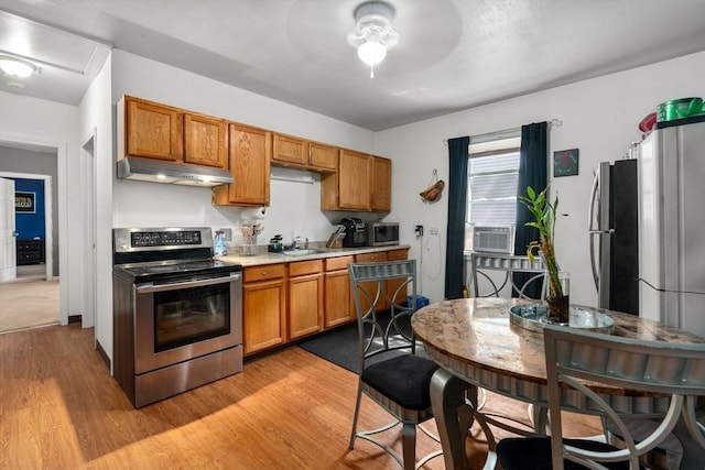 404-406 Franklin St, Springfield, MA 01104 - kitchen with appliances with stainless steel finishes, under cabinet range hood, brown cabinets, light countertops, and light wood-type flooring