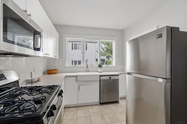 kitchen with white cabinetry, stainless steel appliances, sink, light tile patterned flooring, and decorative backsplash