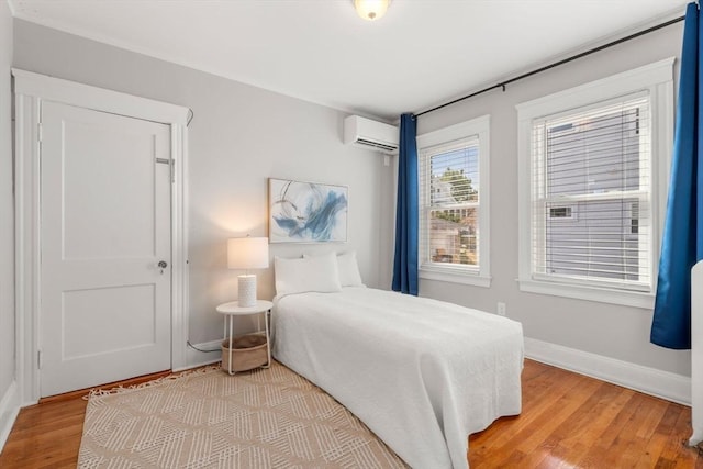 bedroom featuring an AC wall unit and light hardwood / wood-style flooring