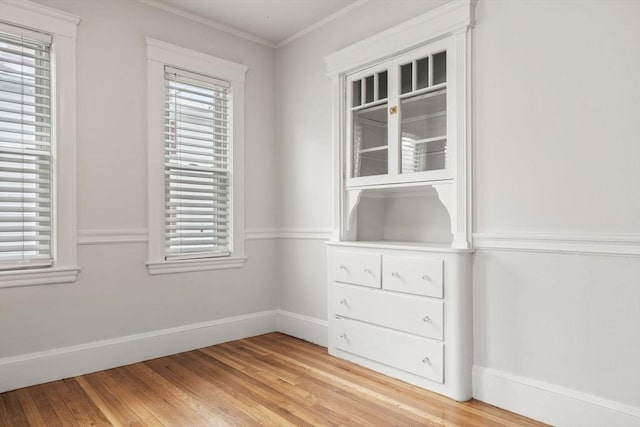 interior space with light wood-type flooring, crown molding, and a wealth of natural light