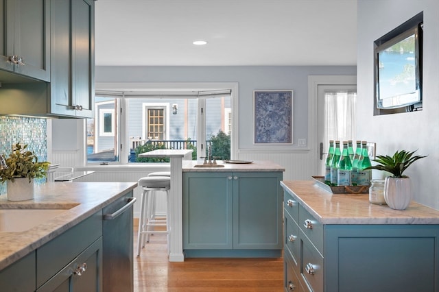 kitchen with dishwasher, light hardwood / wood-style floors, and light stone counters