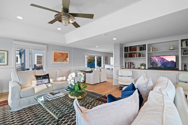 living room featuring light hardwood / wood-style floors, ceiling fan, and built in shelves