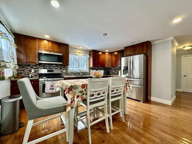 kitchen with crown molding, a center island, light hardwood / wood-style flooring, a kitchen breakfast bar, and stainless steel appliances