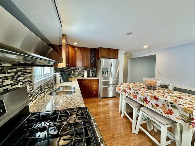 kitchen with sink, crown molding, appliances with stainless steel finishes, backsplash, and light stone countertops