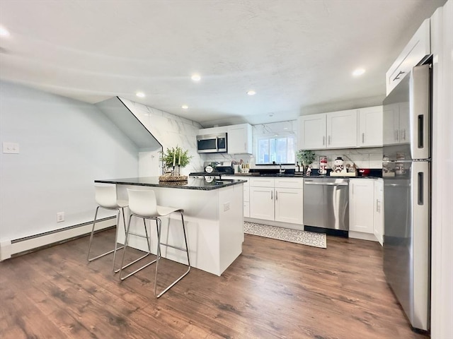 kitchen with white cabinetry, appliances with stainless steel finishes, a center island, and baseboard heating