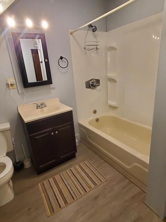 bathroom featuring vanity, bathing tub / shower combination, toilet, and wood finished floors