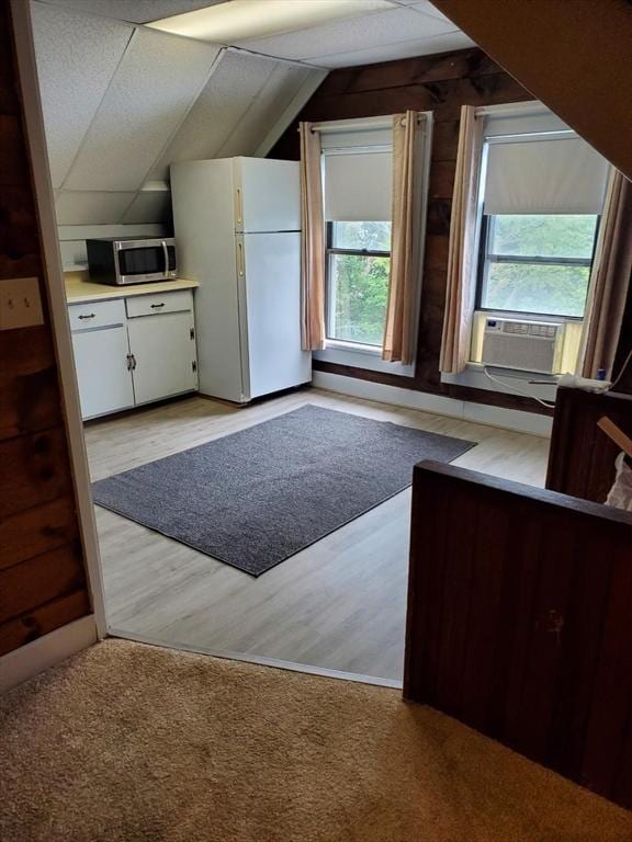 bonus room with lofted ceiling, cooling unit, light wood-style floors, and light carpet