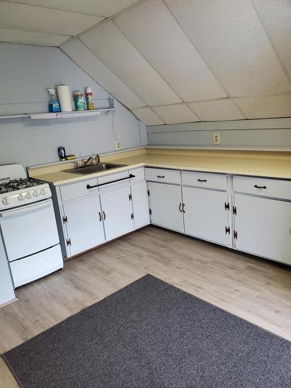 kitchen featuring a sink, white range with gas stovetop, and light wood finished floors