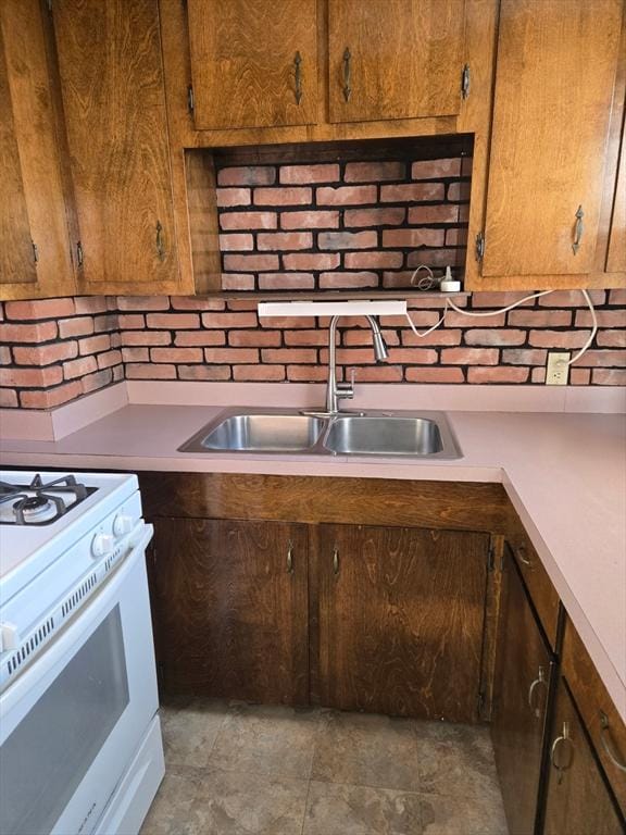 kitchen with light countertops, white range with gas stovetop, and a sink