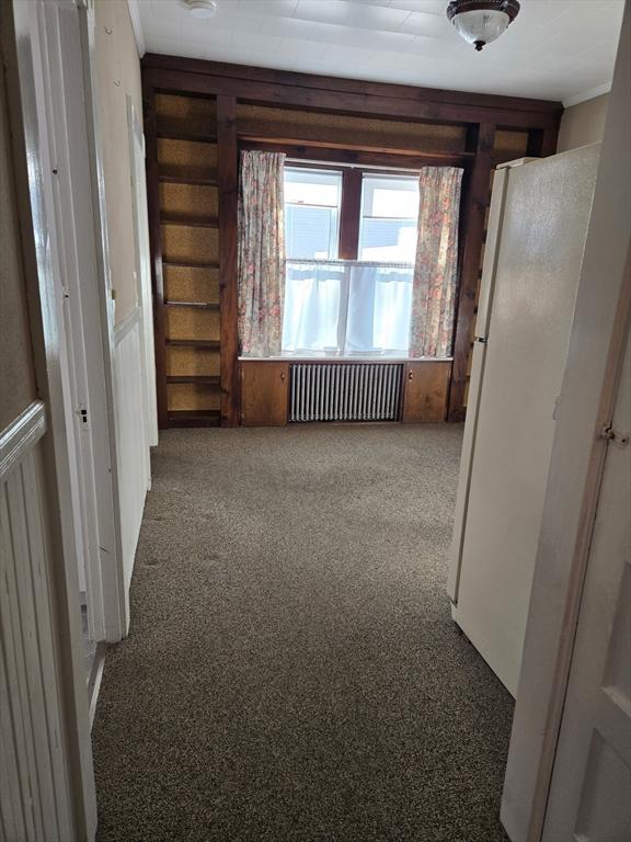 spare room featuring ornamental molding, radiator, and carpet floors