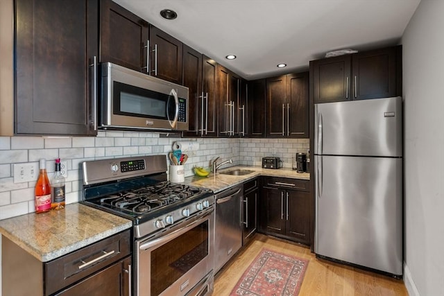 293 D St Unit 2, Boston, MA 02127 - kitchen featuring appliances with stainless steel finishes, light wood-type flooring, dark brown cabinetry, tasteful backsplash, and light stone countertops