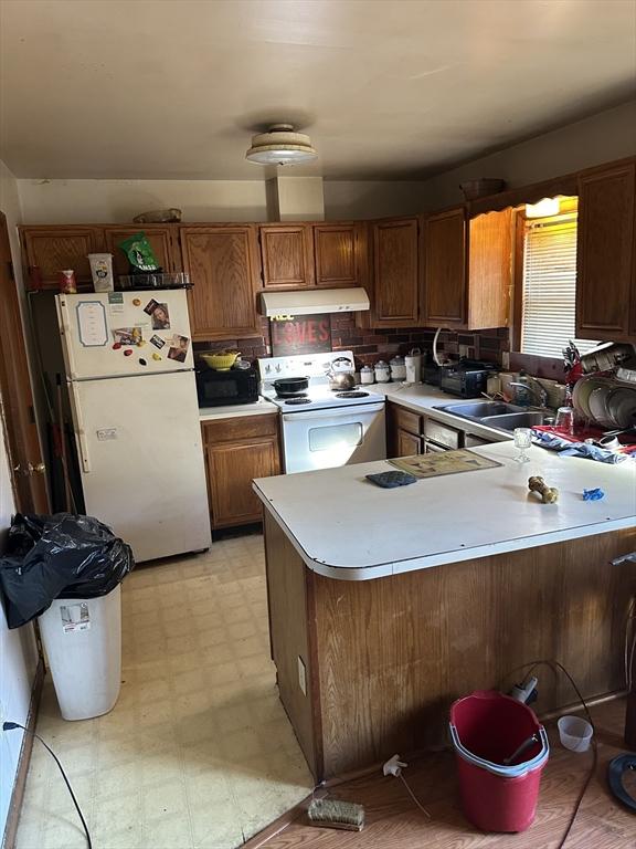 kitchen featuring kitchen peninsula, white appliances, and sink