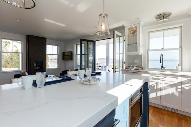 kitchen featuring light hardwood / wood-style flooring, hanging light fixtures, light stone countertops, and white cabinetry