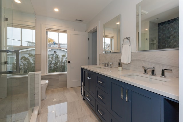 bathroom featuring tile walls, toilet, plenty of natural light, and dual bowl vanity