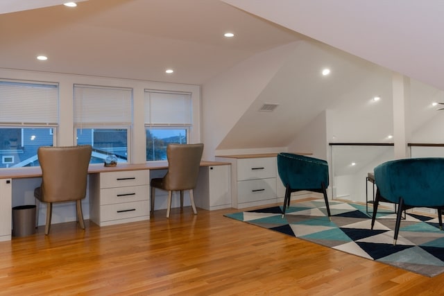 office area with built in desk, vaulted ceiling, plenty of natural light, and light hardwood / wood-style floors