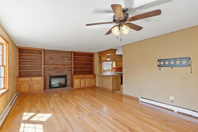 unfurnished living room featuring light wood-type flooring, a brick fireplace, ceiling fan, and a baseboard heating unit