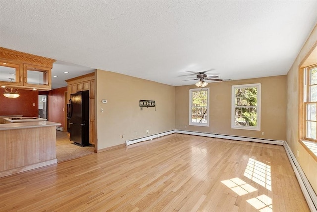 unfurnished living room with baseboards, a ceiling fan, light wood finished floors, and a baseboard heating unit