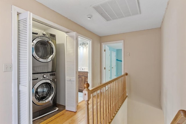 washroom featuring wood finished floors, laundry area, stacked washer / dryer, and visible vents
