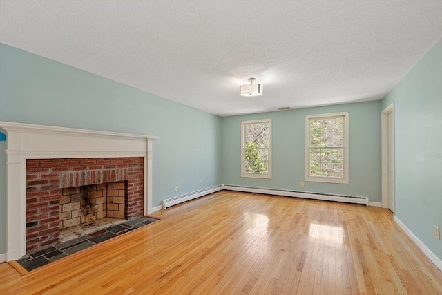 unfurnished living room with wood-type flooring, a brick fireplace, a textured ceiling, baseboards, and a baseboard heating unit