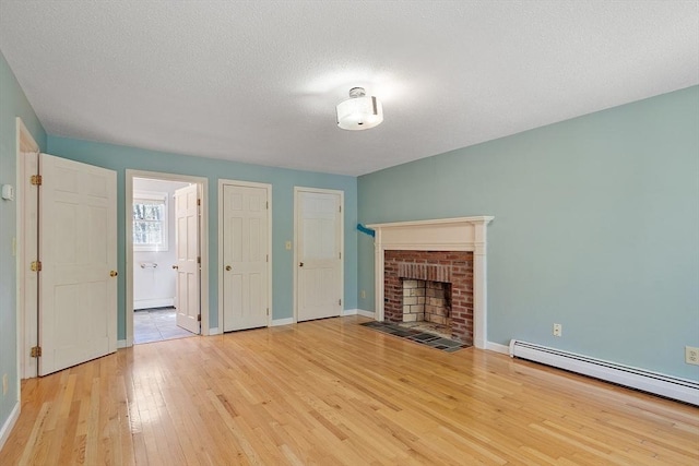 unfurnished living room featuring a brick fireplace, a textured ceiling, light wood-style flooring, baseboards, and a baseboard radiator