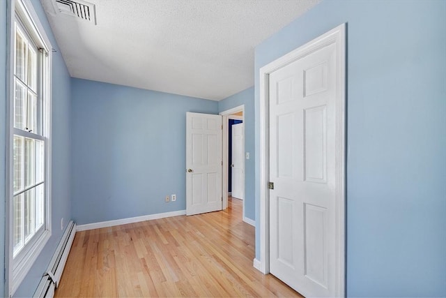 unfurnished bedroom with visible vents, light wood-style flooring, baseboards, and multiple windows