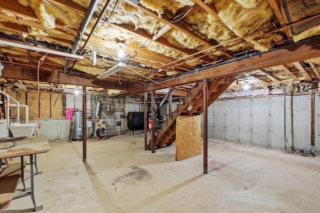 unfinished below grade area featuring water heater, stairway, heating fuel, and a sink