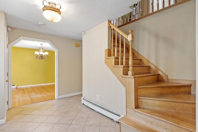 stairs with arched walkways, tile patterned floors, a baseboard heating unit, and a notable chandelier
