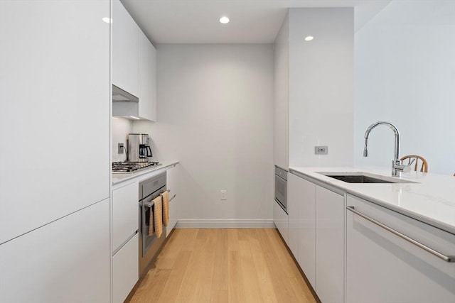 133 Seaport Blvd Unit 1710, Boston, MA 02210 - kitchen featuring a sink, stainless steel appliances, under cabinet range hood, and white cabinetry