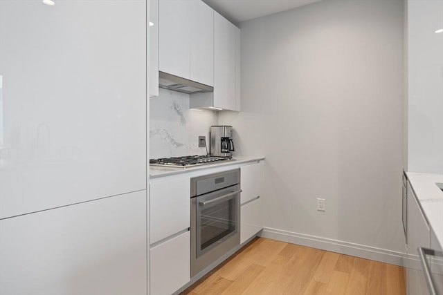 133 Seaport Blvd Unit 1710, Boston, MA 02210 - kitchen featuring light countertops, stainless steel appliances, baseboards, white cabinetry, and light wood-type flooring