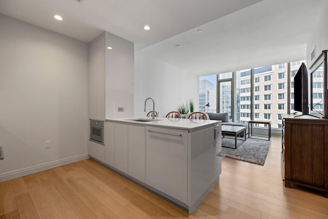 133 Seaport Blvd Unit 1710, Boston, MA 02210 - kitchen featuring light wood-style floors, a sink, a peninsula, and stainless steel oven