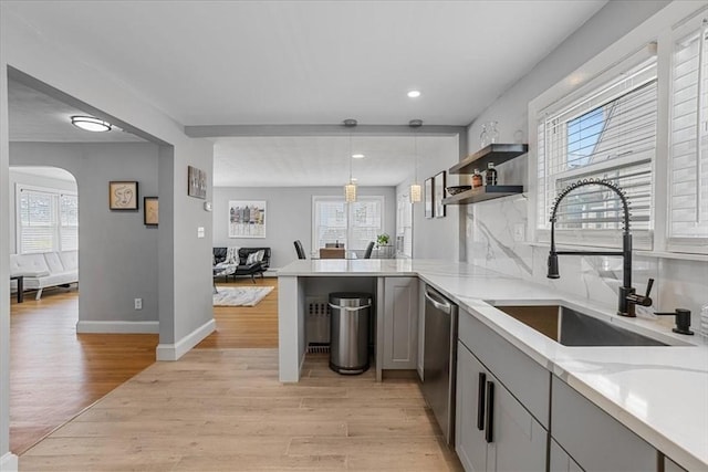 kitchen featuring light wood-style floors, arched walkways, a sink, and dishwasher