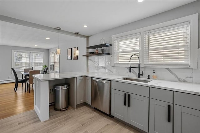 kitchen featuring a sink, stainless steel dishwasher, gray cabinets, decorative backsplash, and light wood finished floors