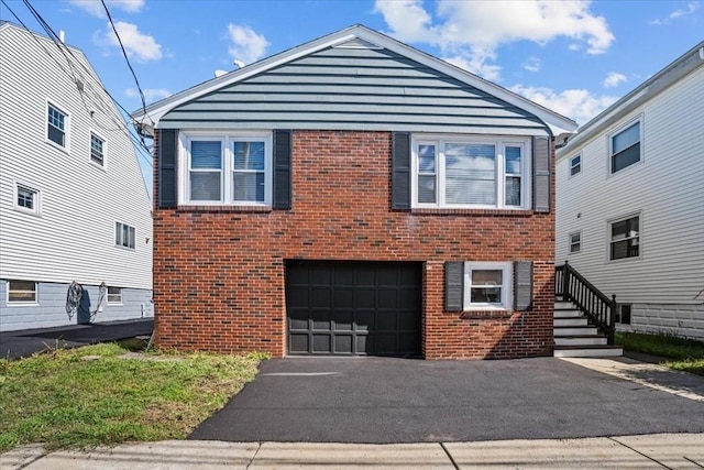 split level home featuring driveway, a garage, and brick siding