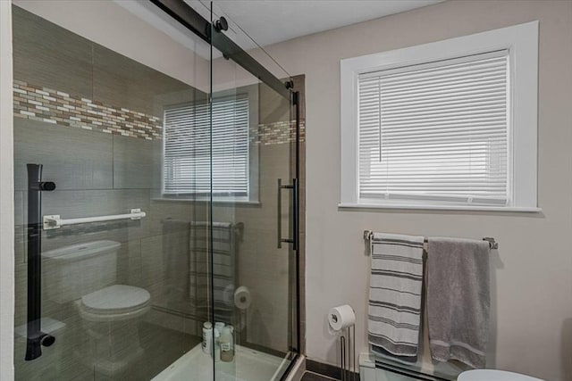 bathroom featuring baseboard heating, plenty of natural light, a shower stall, and toilet