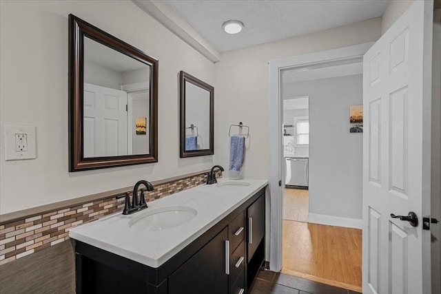 bathroom with double vanity, a sink, and wood finished floors