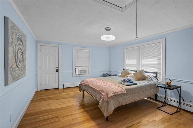 bedroom with light wood-style floors, attic access, ornamental molding, and a baseboard heating unit