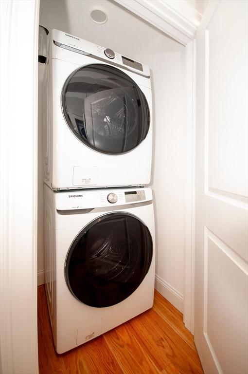 laundry room featuring stacked washer and dryer, laundry area, and light wood finished floors