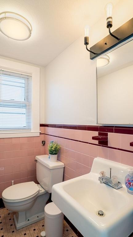 bathroom featuring a wainscoted wall, a sink, tile walls, and toilet