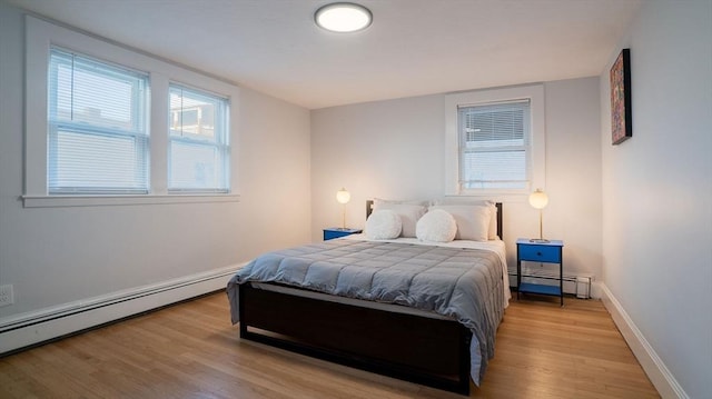 bedroom with a baseboard heating unit, a baseboard radiator, baseboards, and light wood-style floors