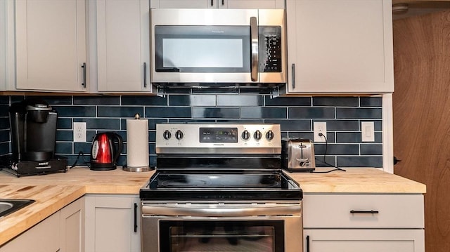 kitchen featuring stainless steel appliances, butcher block counters, and decorative backsplash