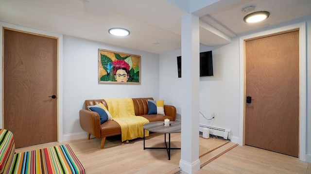 living room featuring a baseboard radiator, baseboards, and light wood finished floors