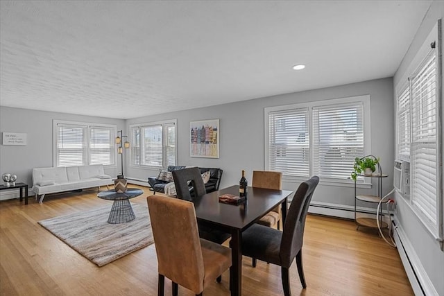 dining space featuring light wood finished floors, baseboard heating, and recessed lighting