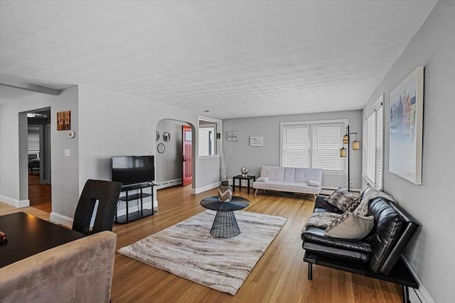 living area featuring arched walkways, wood finished floors, and baseboards