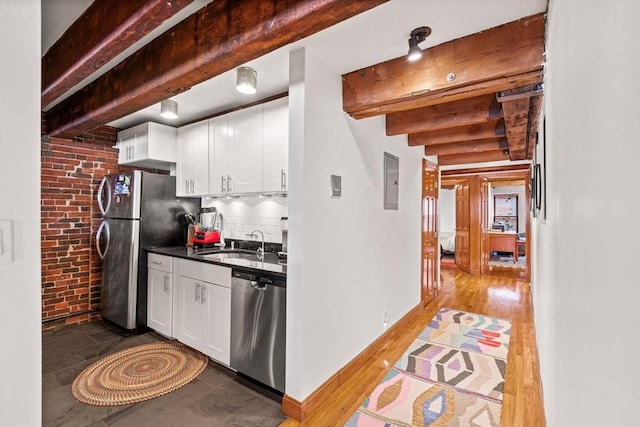 kitchen featuring beamed ceiling, appliances with stainless steel finishes, sink, and white cabinets