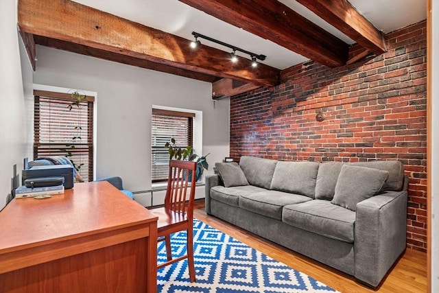 living room featuring beamed ceiling, a baseboard radiator, brick wall, and light wood-type flooring