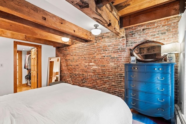 bedroom with beam ceiling and brick wall