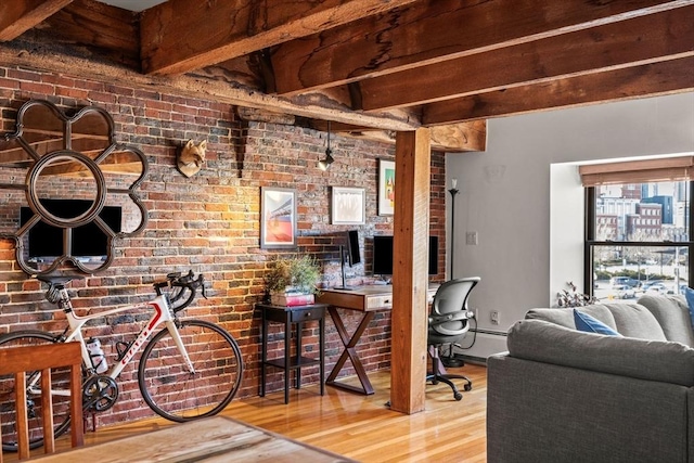 interior space featuring beamed ceiling, wood-type flooring, brick wall, and baseboard heating