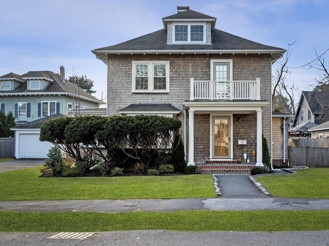 view of front facade with a balcony, a front lawn, and a garage